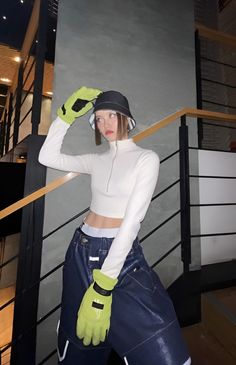 a woman in white top and blue jeans with yellow gloves standing next to stair railing