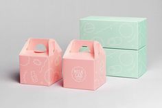 two pink and green boxes sitting next to each other on a gray surface with white writing