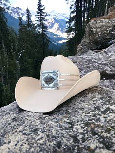 Everest features a traditional western buckle with a Jasper stone focal point highlighted with three hammered silver metal straps around a cream canvas cowboy hat. Proudly American Made. Our hats are manufactured in Mexico and details added by hand in Los Angeles, CA using the highest quality materials. Sizing S/M 19in-22.75in | 48cm-57.5cm L/XL 19.5in-23.25in | 49.5cm-59cm *Please allow up to 6 weeks for production and shipping. Embark on a style odyssey with Everest, where Jasper, a gem exuding earthy beauty and cultural significance, imparts a distinctive charm to your journey through the timeless allure of the Wild West. Cowboy Hat Pins, Earthy Beauty, Garden Party Bridal Shower, Parisian Summer, Western Buckles, Bridal Fabric, The Wild West, Metal Straps, Hand Painted Rocks