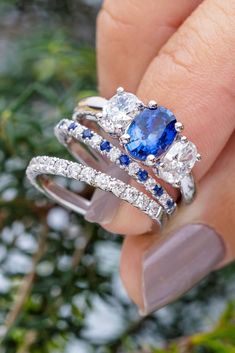 a woman's hand holding two rings with blue and white stones