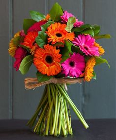 a bouquet of colorful flowers sitting on top of a black table next to a gray wall