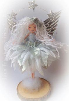 an angel figurine sitting on top of a piece of wood with stars above it