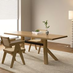 a dining room table with two chairs and a vase on the rug next to it