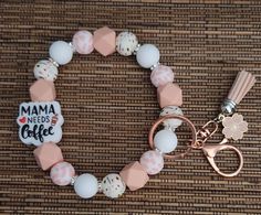 a pink and white beaded bracelet with a keychain on top of it