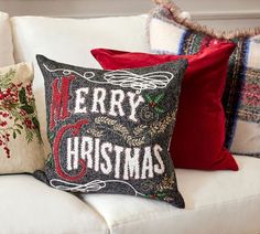 two christmas pillows sitting on top of a white couch