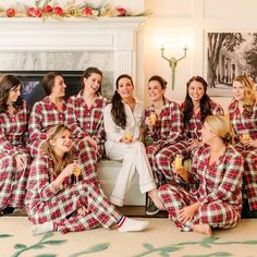 a group of women in plaid pajamas sitting next to each other and drinking wine together