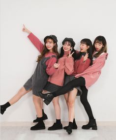 four young women posing in front of a white wall