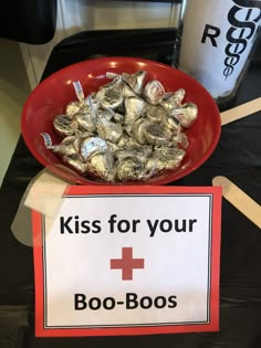 a red bowl filled with candy next to a sign that says kiss for your boo - boos