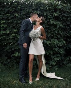 a bride and groom kissing in front of a hedge