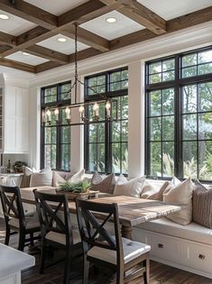 a living room filled with lots of furniture next to two large windows covered in wooden beams