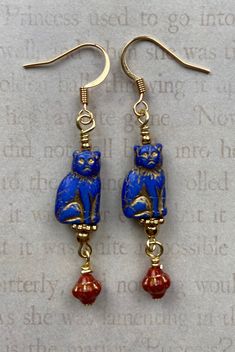 These beautiful Czech glass kitties are a rich cobalt blue with a gold wash that highlights all their precious details. I added gold accent beads and little red Czech glass beads. Purrfect for the cat lover in your life or for your very own kitty loving soul! I have these cats in several colors. Let me know if you can't find the color you want. Earring hooks are 18k gold plated. Lever back hooks are available upon request. All of my earrings come on a hand stamped earring card and are lovingly w Blue Cat Design Jewelry For Gift, Blue Cat Design Jewelry As Gift, Blue Jewelry With Cat Design For Gift, Crazy Cat Lady Gifts, Czech Glass Jewelry, Stamped Earrings, Glass Cat, Cat Lady Gift, Indie Jewelry