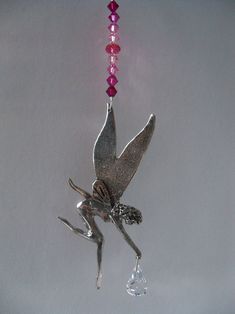 a silver bird with pink beads hanging from it's side