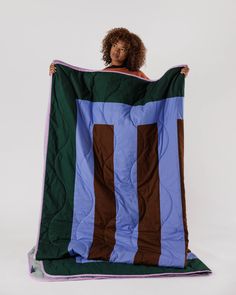 a woman is holding up a large blanket