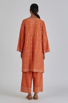 Rust orange silk kurta featuring kashmiri resham embroidered floral motifs in a phiran style silhouette. Comes with matching pant. - Aza Fashions Orange Chikankari Embroidery Palazzo Set For Designer Wear, Orange Chikankari Embroidery Palazzo Set, Orange Chikankari Embroidery Lawn Suit For Eid, Orange Chikankari Embroidery Palazzo Set For Eid, Orange Chikankari Embroidery Palazzo Set For Diwali, Festive Orange Palazzo Set With Chikankari Embroidery, Diwali Orange Chikankari Embroidery Palazzo Set, Orange Silk Sets With Resham Embroidery, Designer Orange Kurta With Chikankari Embroidery