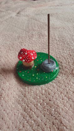 a small toy mushroom sitting on top of a green base with two sticks sticking out of it