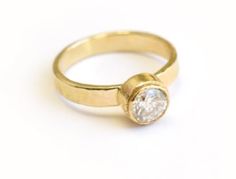 a yellow gold ring with a diamond on the top and bottom, against a white background