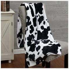 a black and white cow print blanket sitting on top of a chair next to a wooden wall