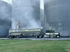 a large truck driving down a road next to two silos