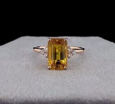 an orange and yellow diamond ring sitting on top of a white cloth