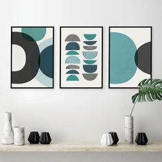 three abstract paintings hang on the wall above a table with vases and potted plant