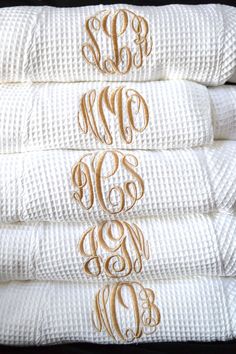 three white towels stacked on top of each other with monogrammed initials in the middle