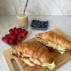 two croissants on a cutting board with berries and milk