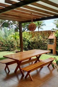 a wooden picnic table sitting under a pergolated roof next to a lush green yard