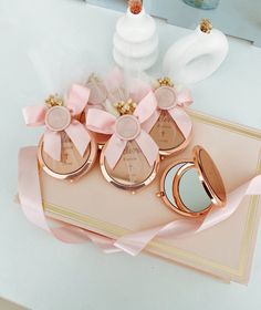 three small round compact mirrors with pink bows on them and one is open to show the contents