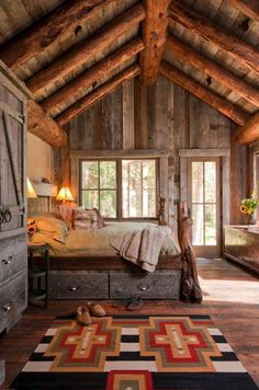 a bedroom with wooden walls and ceilings has a large bed in the center, along with an area rug on the floor