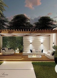 an outdoor living area with couches, tables and lights on the side of it