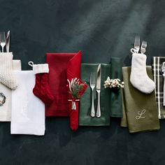 four napkins with silverware and christmas decorations on them are lined up against a black background