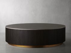 a black and gold round coffee table on a grey surface with a white wall in the background