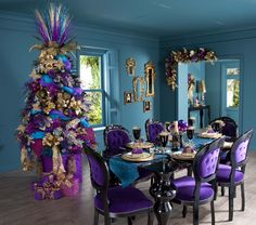 a dining room table with purple chairs and a christmas tree in the corner behind it