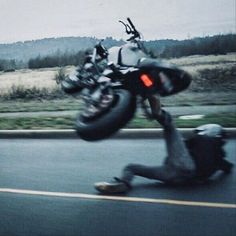 a man falling off his motorcycle on the road