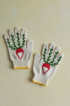 two white gloves with red and green designs on them, one has a radish in the middle