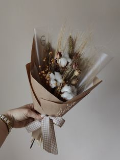 a person holding a bouquet of flowers in their hand with cotton floss tied around it