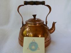 an antique copper tea kettle with a label on it