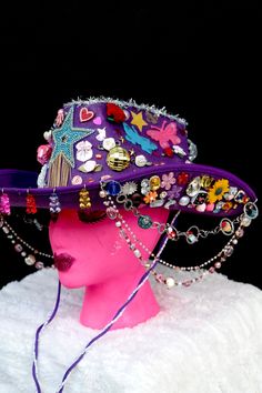 All eyes will be on you in this fabulous purple cowgirl hat covered to the brim with rainbow galore. From the front hang colorful gummy bears and from the sides hang three colorful beaded chains. The hat is covered with stars, hearts, flowers, rhinestones, butterflies, pearls, disco balls, mini animals and treats, and silver tinsel. It has a purple and lace neck tie. Purple Cowgirl Hat, Purple Cowgirl, Mini Animals, Silver Tinsel, Lace Neck, Handmade Things, Cowgirl Hat, Disco Balls, Cow Girl