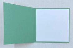 an open green and white folder on a white surface with a blank paper in the middle