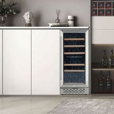 a wine cooler in the middle of a kitchen with bottles and glasses on it's doors