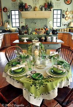 the table is set with green dishes and place settings for two people to eat at