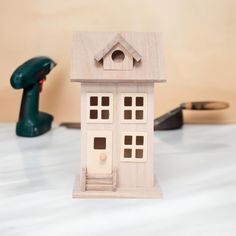 a small wooden house sitting on top of a table next to a pair of scissors