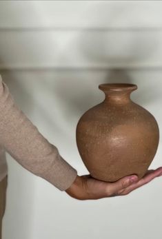 a person holding a brown vase in their hand