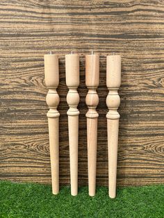 four wooden candles are lined up on the grass