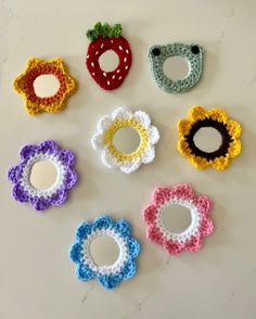 six crocheted flowers are arranged in the shape of flower petals on a white surface