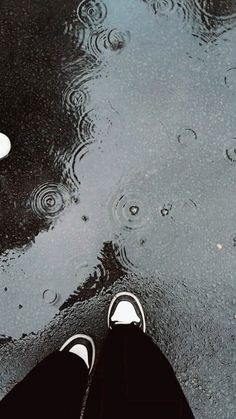 a person standing in the rain with their feet up