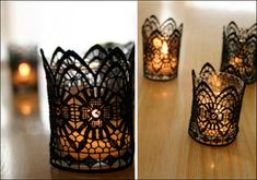 lace candle holders with candles in them sitting on a wooden table next to each other