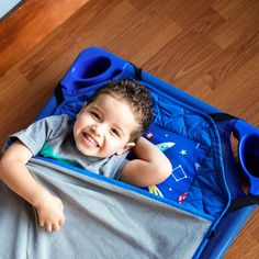 a little boy that is laying down in a suitcase