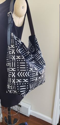 "Beautiful shoulder tote / hobo tote bag / bucket tote. African print in black and white. Adjustable Vegan leather shoulder strap that looks like real leather, with metal buckle. Bag lining made with sturdy cotton canvas. Large inside pocket for your cell phone and keys. Open top bag but deep enough to keep your valuables safe. LARGE SIZE TOTE = 18\"W X 17\"H X 5\" Adjustable shoulder strap 24 - 28\" Made in Newark, New Jersey by Kirtam Designs Inc. Hand wash and hang to dry. SOCIAL CAUSE : The Kente Print, Bag Lining, Buckle Bag, Hobo Tote Bag, Bucket Tote, Kente Cloth, Social Cause, Handbag Outfit, Hobo Handbags