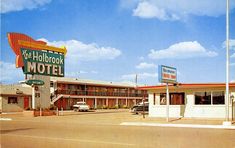 an old motel with cars parked in the parking lot next to it and a blue sky